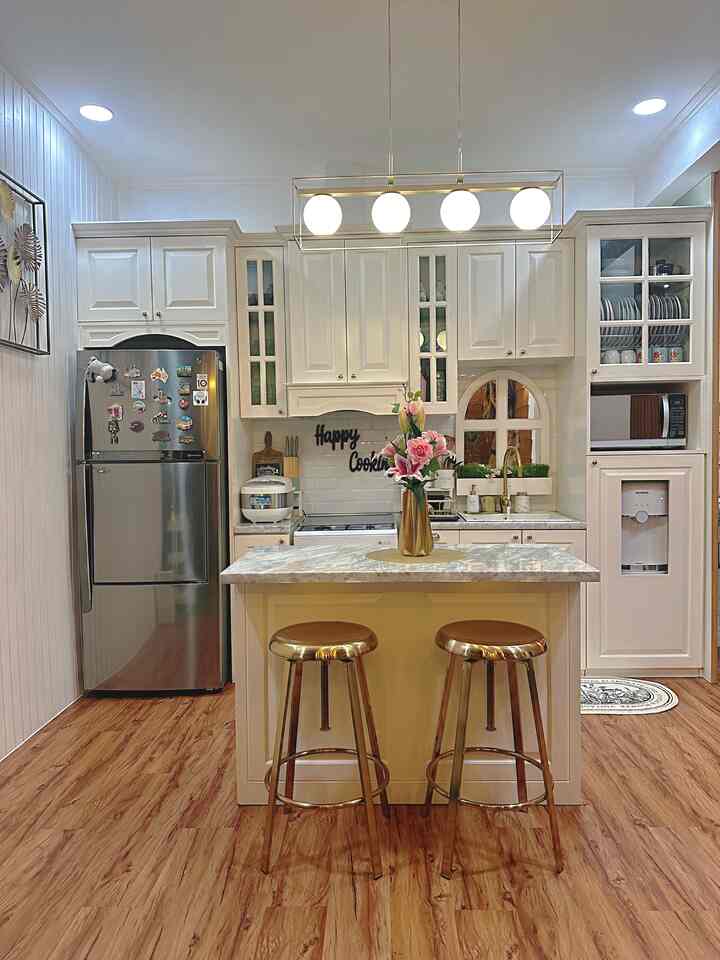 Small kitchen space in dominant white and wood tones, featuring a kitchen island with gold accent stools, creating a cozy atmosphere