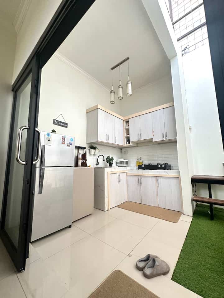 Minimal kitchen in white and green tones, semi-outdoor style with artificial grass carpet dividing the space