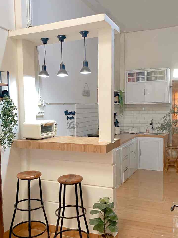 Minimal kitchen space featuring white and wood tones, with a minibar and bar stools creating a cozy atmosphere