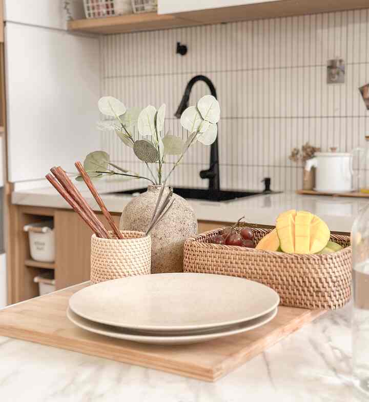 Natural color and beige toned kitchen featuring plates and utensils on a wooden cutting board with rattan baskets creating a cozy kitchen atmosphere