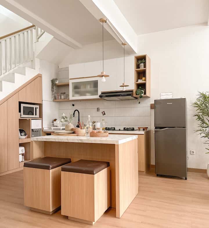 White and wood tone kitchen featuring a minimalist dining island with trays and pendant lights creating a simple, clean interior