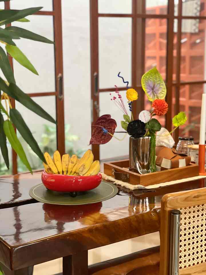 Warm brown wood tone dining room featuring a glossy wooden table with a red fruit bowl and colorful vase creating a cozy atmosphere