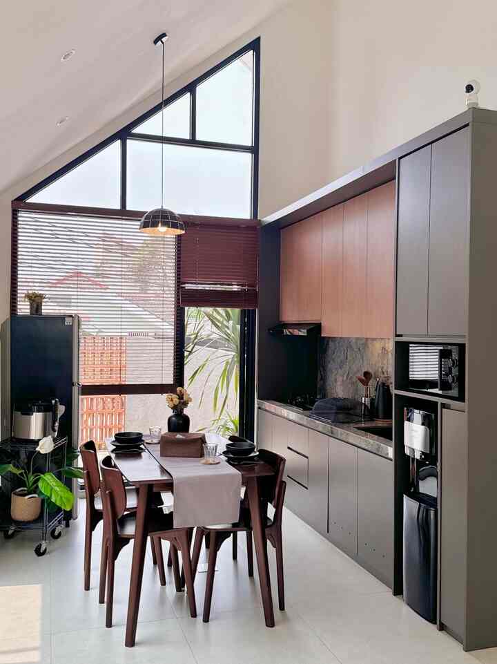 Kitchen dan dining di depan, terasa lebih luas dan terang karena penuh akan pencahayaan. Kami memilih warna abu-abu agar ada sedikit sentuhan industrial, tapi tetap terasa hangat dengan tambahan warna kayu. 

Dining ini adalah salah satu tempat favorit kami, karena view meja makan yang langsung ke area taman samping. Posisinya berada di area kitchen agar mudah dalam penyajian dan juga lebih efisien selama aktifitas makan. 

Peralatan makan keramik hitam menjadi favorit kami, bikin suasana makan lebih terasa modern. Kami pilih taplak meja yang water resist, agar aman dari tumpahan makanan atau minuman dan gampang dibersihkan. 

#mejamakanminimalis #mejamakan #mejamakankayusolid #kitchenset #kitchensetindustrialmodern #woodenblind #potkeramikhitam #tempattisu #taplakmejaabu #dapurminimalis #dapurmodern #peralatanmakan #piringkeramik #inspirasiruangmakan #inspirasidapur #tableset #setmejamakan #modeldapurcantik