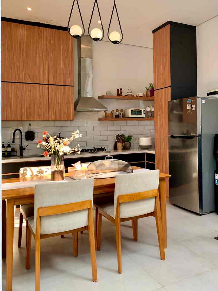 Natural-toned kitchen featuring wooden dining table and chairs, white walls, and stainless steel refrigerator in a clean layout