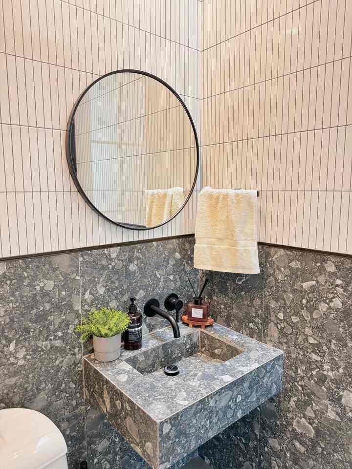 Gray stone sink bathroom featuring a round black-framed mirror and white towel, creating a clean modern atmosphere