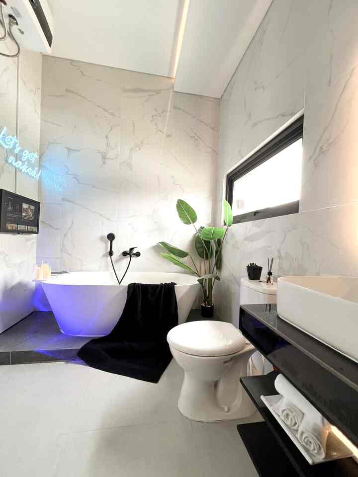 Kamar mandi di kamar utama Rumah Bujangan ini memiliki ukuran  2,15 x 3,5m dan bernuansa modern minimalist.
•
Lantai dan dinding menggunakan material granit ukuran 60x60. Penggunaan granit warna putih bertujuan untuk menimbulkan kesan clean dan luas.
•
Kenyamanan di kamar mandi termasuk dalam prioritas saya, untuk itu saya sengaja memasang bathtub air panas lengkap dengan smart tv agar semakin menambah kesan mewah dan nyaman.
•
Selain menggunakan material full granit, untuk menambah aesthetic dan unik saya menambahkan lampu neon flex bertuliskan “lets get naked!”. 

#granitkamarmandi #granit60x60 #closet #closettoto #bathtub #cerminled #cermintouchscreen #KamarMandiMinimalis #KamarMandiMinimalist #InspirasiKamarMandi