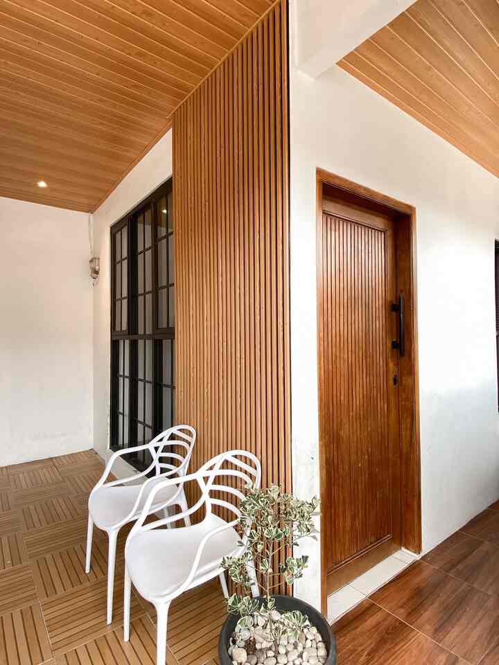 Wood tone and white veranda space featuring modern outdoor chairs and a simple entrance