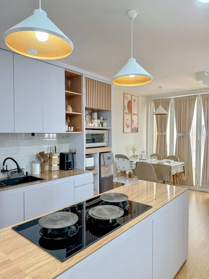 ✨ Dapur dan Meja makan minimalis ini benar-benar salah satu area favoritku di rumah, apalagi dipadukan dengan desain dapur Japandi yang simpel dan fungsional. Mari aku jelaskan setiap detailnya! ✨

Dapur dengan Konsep Japandi: Area dapurku mengusung gaya minimalis dengan dominasi warna putih dan aksen kayu natural yang memberikan kesan bersih dan tenang. Kabinet dapur tertutup membantu menyembunyikan peralatan agar ruangan tetap terlihat rapi.

Countertop Kayu: Aku memilih countertop kayu yang dipadukan dengan backsplash ubin putih bergaya subway tile. Ini memberikan keseimbangan antara kehangatan material kayu dan kesan modern dari ubin.

Rak Terbuka dan Penyimpanan: Aku sengaja menambahkan rak terbuka untuk memajang barang-barang kecil seperti cangkir, toples bumbu, dan dekorasi sederhana. Rak ini memberikan aksen estetik tanpa membuat ruangan terlihat berantakan.

Peralatan Dapur: Kompor tanam dengan desain minimalis menjadi centerpiece di area dapur. Aku juga memilih teko, dispenser air, dan alat masak lainnya yang senada dengan tema ruangan, semuanya simpel dan modern.

Pencahayaan Dapur: Lampu gantung di area dapur memiliki desain yang sama dengan lampu makan, menciptakan kesinambungan visual antara dua area. Cahaya hangat dari lampu ini membuat dapur terasa lebih welcoming.

Dekorasi Dapur: Untuk memperkuat tema Japandi, aku menambahkan sentuhan kecil seperti pot tanaman mini, wadah kayu untuk alat masak, dan organizer sederhana untuk menyimpan alat makan.

Keseluruhan Ruangan: Transisi antara dapur dan meja makan dibuat seamless, tanpa sekat, sehingga ruangan terasa lebih luas dan terang. Warna beige, putih, dan aksen kayu membuat kedua area ini terlihat harmonis dan menyatu.

Dengan desain ini, dapur dan ruang makan tidak hanya berfungsi sebagai tempat memasak atau makan, tapi juga menjadi area keluarga untuk berkumpul dan berbagi cerita. ❤️

📌 Hashtags:
#dapurminimalis #mejamakanminimalis
#komportanam #alaspanci #babychair #dispenser #walldecor #airfryer #sutilaesthetic #inspirasiruangmakan #peralatanmakan 