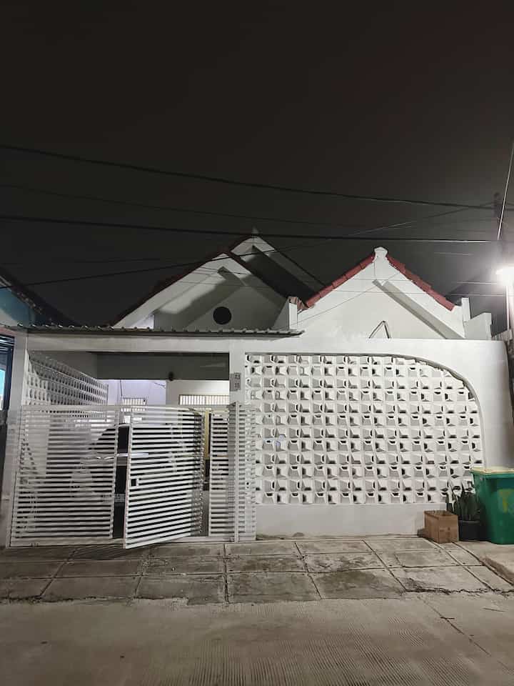 Fasad rumah sederhana berkonsep minimalis modern. Tinggi pagar roster 3 meter dan berpagar besi horizontal terdapat bukaan pintu tengah. 

Roster pagar kami pilih 2 motif. 
Roster “baling-baling”, permukaan timbul pada pagar depan rumah dan bagian atas dibuat melengkung. 
Roster “donat”, permukaan datar pada pagar samping rumah, fungsinya untuk privasi dengan tetangga sebelah dan menjaga sirkulasi udara ke teras. 

Cat tembok rumah kami memilih putih, memberi kesan fasad rumah ini luas dan bersih. 

Kanopi teras standard saja, dan rumah kami masih pakai 3 gunung atap asli dari bawaan rumah. Genteng atap juga masih asli dari bahan tanah liat. Sederhana memang. 

Tanaman Sansivera menghiasi depan rumah kami dan tempat sampah besar sesuai kebutuhan makaimal pembuangan sampah. Depan rumah juga ada lampu jalan bawaan dari aslinya. 

Teras Dalam Rumah, ini dibalik belakang pagar roster ya. Teras simpel namun luas ini terdapat tanaman sansivera dengan pot tembok setinggi 1 meter. Kursi keju dan coffee table estetik menghiasi teras simpel kami. Lantai terrazo ukuran 40cm x 40cm dan batu coral putih. Teras ini beratap terbuka. Dan pada malam hari kami dapat cahaya lampu dari balik roster yang membuat teras ini terlihat cantik. Oiya, diatas teras ada glass block ini adalah kamar mandi dalam kamar kami. 
#PagarRumahMinimalis #PagarRumah #CatTembok #WarnaCatPagar #KursiTeras #MejaTeras #TanamanHias #BatuCoral #NomorBoardRumah #AtapRumah #PagarRoster #PagarBesi #CatSemenEkspos #LantaiKeramik #KeramikTerrazo #GlassBlock #FasadRumah #Ohouseseason9 #ummaHaus #ummaarrayyan #InspirasiFasad #StyleFasad

