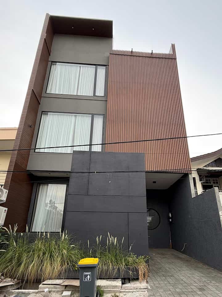 JEAN HOUSE Home Facade ✨

Fasad rumah ini memancarkan gaya modern minimalis yang memukau! Kombinasi warna hitam elegan, abu-abu yang netral, dan aksen kayu cokelat vertikal memberikan sentuhan hangat sekaligus mewah. Jendela besar yang menjulang dari lantai ke lantai menciptakan kesan megah dan terang, seolah mengundang cahaya alami masuk ke setiap sudut rumah. Detail unik seperti elemen kaca bundar di dinding menambah karakter yang membuat rumah ini tampil beda dan mencuri perhatian. Dengan desain yang berani dan penuh estetika, rumah ini benar-benar menjadi simbol kemewahan yang sederhana namun berkelas!

Saat malam hari, fasad rumah ini semakin memukau dengan pencahayaan yang menonjolkan keindahan desainnya. Lampu-lampu hangat menyinari aksen kayu vertikal, menciptakan bayangan yang dramatis dan menambah kesan elegan. Jendela besar memancarkan cahaya dari dalam, membuat rumah terlihat hidup dan ramah. Area pintu utama yang diterangi dengan lembut memberikan nuansa hangat yang mengundang, sementara elemen bundar di dinding terlihat semakin artistik dengan permainan cahaya dan bayangan. Di bawah langit malam, rumah ini benar-benar menjadi sorotan yang memikat!

#fasadrumah #warnacatrumah #catrumah #cattekstur #inspirasifasad #stylefasad #modern #contemporary #industrial #gelap #conwood #garden #alangalang #tongsampah   #pinturumah