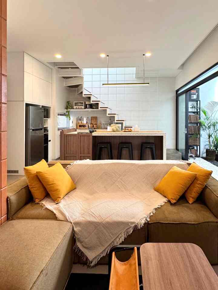 Natural-toned open floor plan living room and kitchen featuring sofa and kitchen island with a warm atmosphere