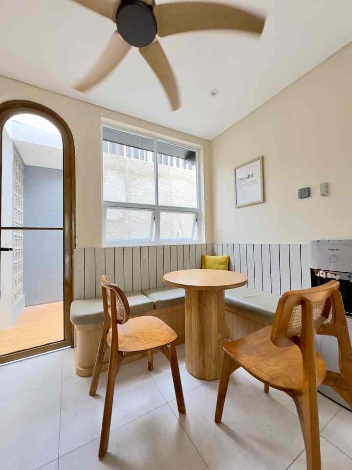 Wood-tone and white corner dining room featuring a round dining table, two wooden chairs, and bench seating in a modern setting
