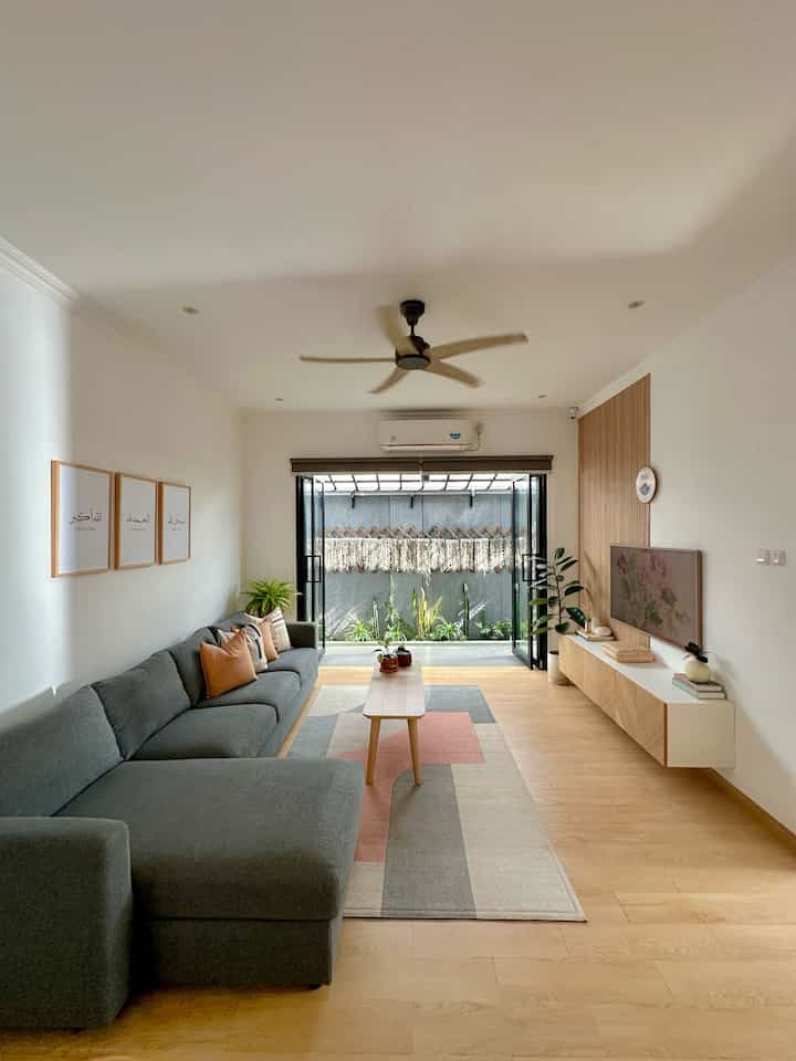 Modern living room with white walls and natural wood tones featuring a gray sectional sofa and coffee table creating a cozy atmosphere