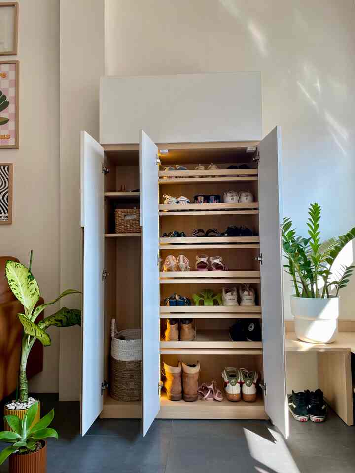 White and natural color entrance featuring shoe storage cabinet and plants in a modern, bright space
