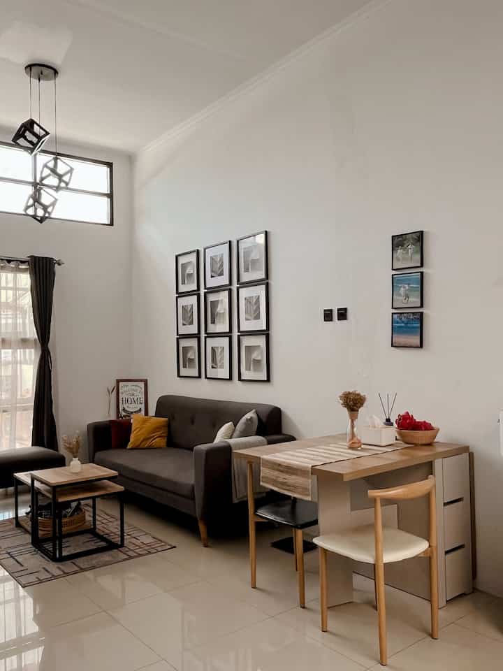 Natural modern living room with white walls, wood-tone dining table, and brown sofa