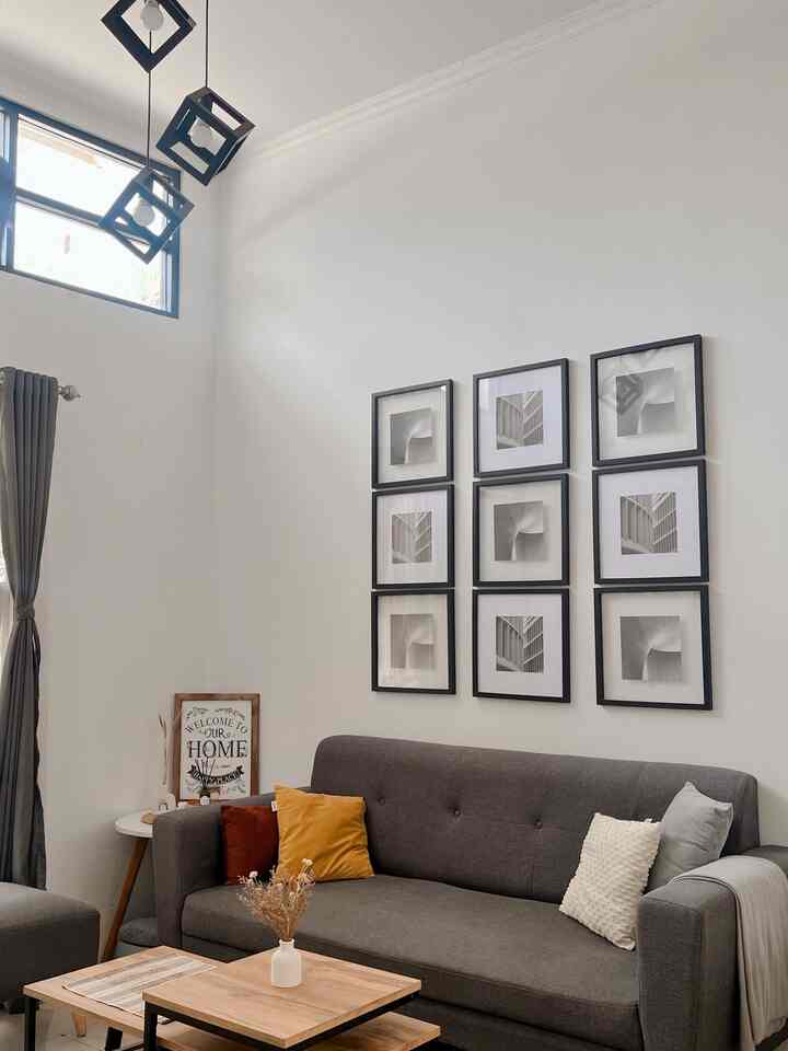 A white and gray toned living room featuring a dark gray sofa, wooden coffee table, and nine framed pictures on the wall creating a simple modern atmosphere