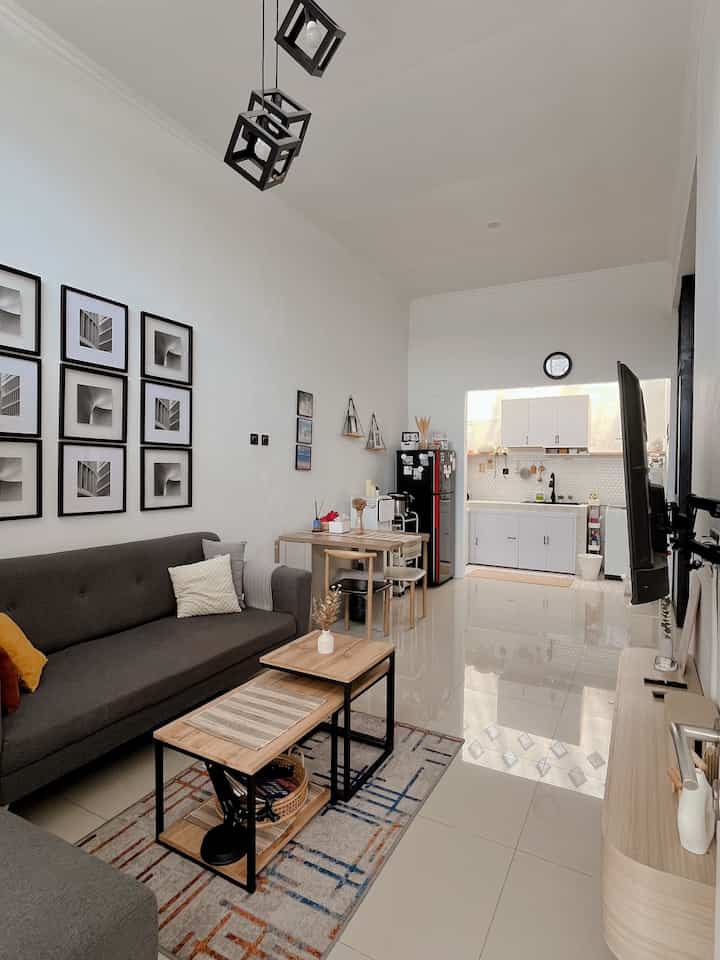 White, gray, and wood tone open space living room and kitchen featuring sofa and coffee tables with cozy atmosphere