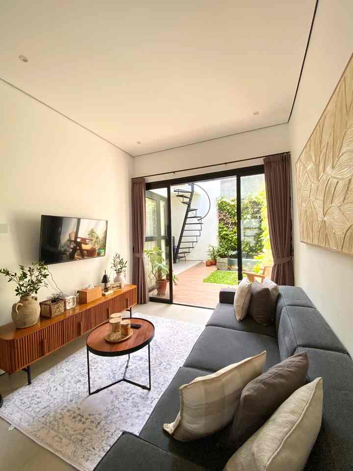 A living room with white walls and wood tone furniture featuring a gray sofa and coffee table, creating a modern natural atmosphere