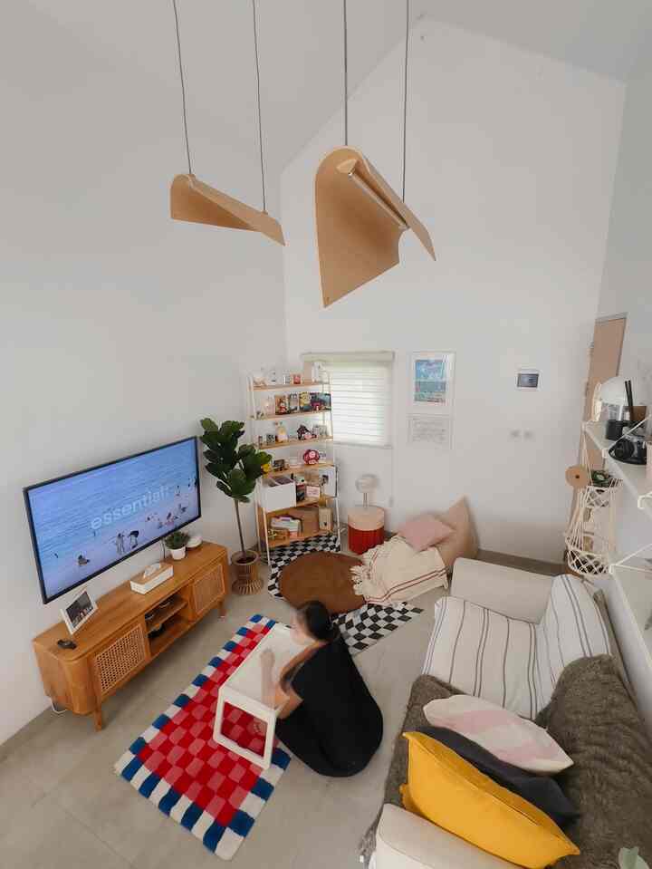 White walls and brown furniture define a compact living room featuring striped sofa, bean bag, and TV stand in a cozy setting