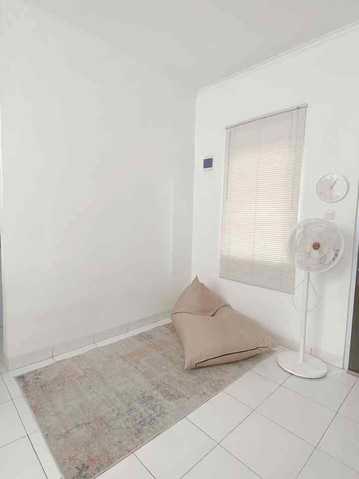 White-toned small room featuring a beige bean bag and patterned carpet in a simple setting