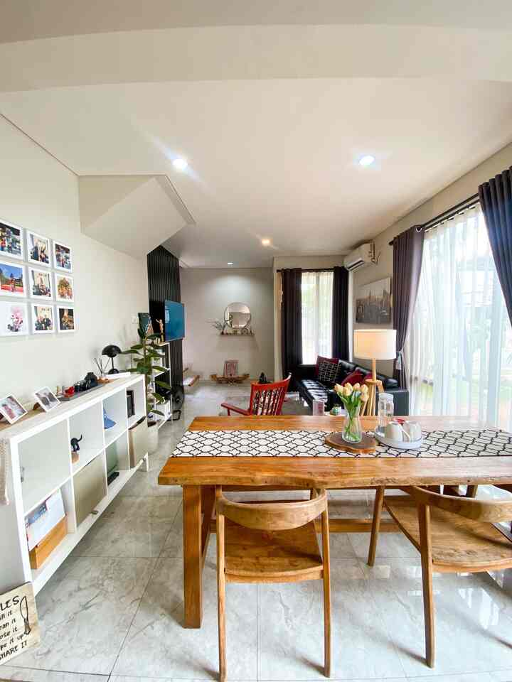 White and brown toned living and dining area featuring wooden dining table and black sofa creating a cozy space