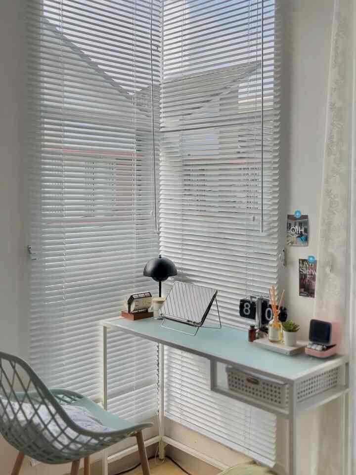 Small home office space in white and mint tones featuring a simple desk and chair with a bright, clean atmosphere