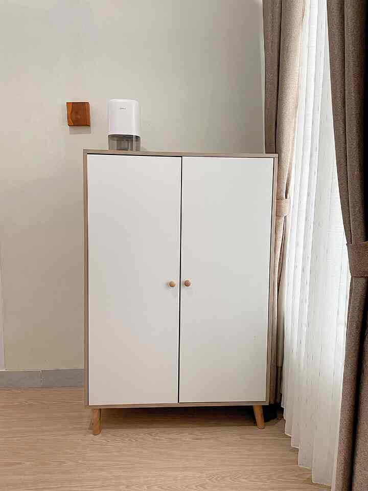 Modern small room in white and brown tones featuring a simple wardrobe and curtains by the window