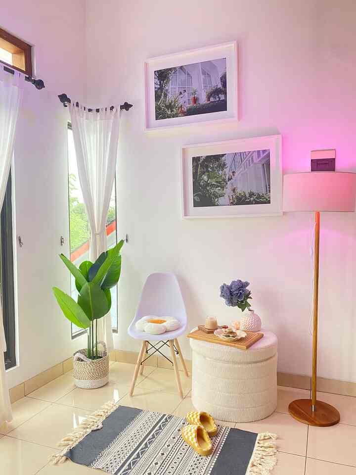 White-toned living room featuring a Bohemian carpet, stool, and green plant creating a cozy atmosphere