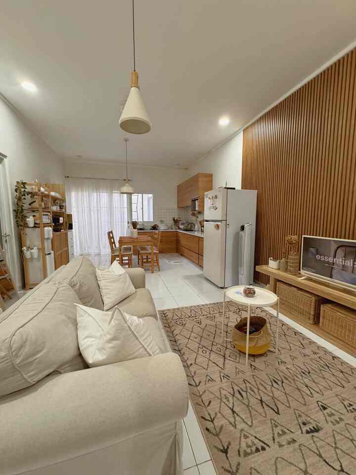 White and brown toned open plan living room and kitchen featuring natural wood furniture and pendant lights in a cozy space