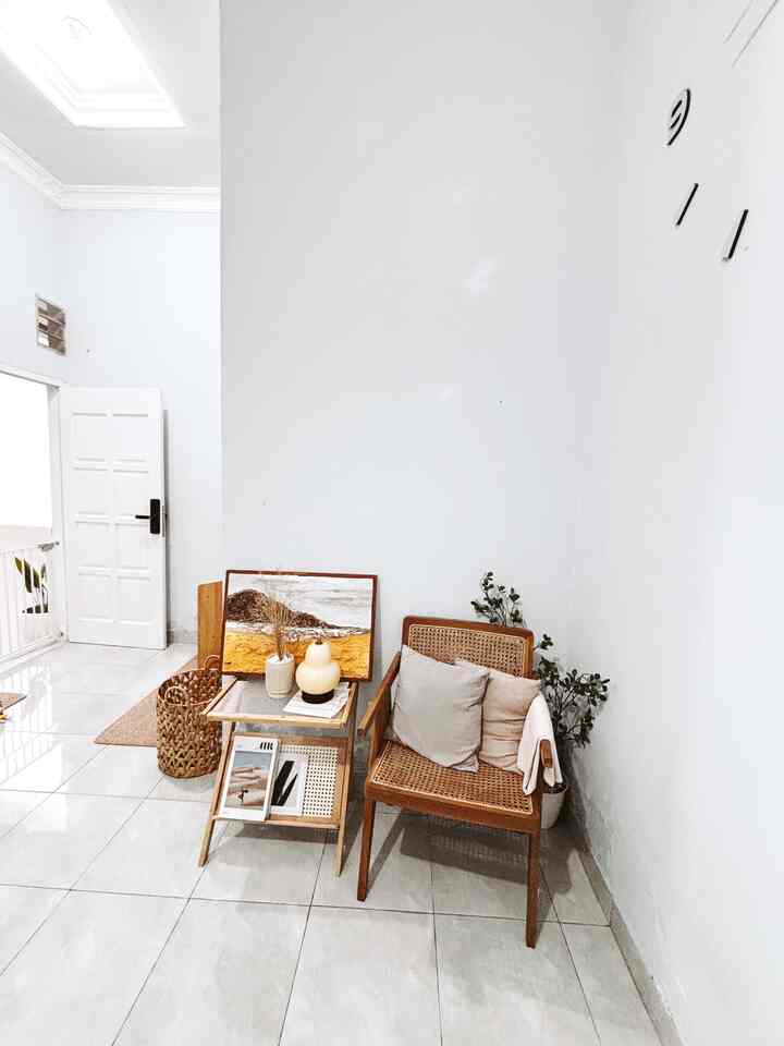 Bright white-walled space featuring natural wood tone armchair and side table arranged in cozy cafe style