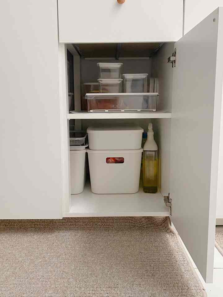 White-toned cabinet interior featuring neatly organized transparent and opaque plastic storage containers