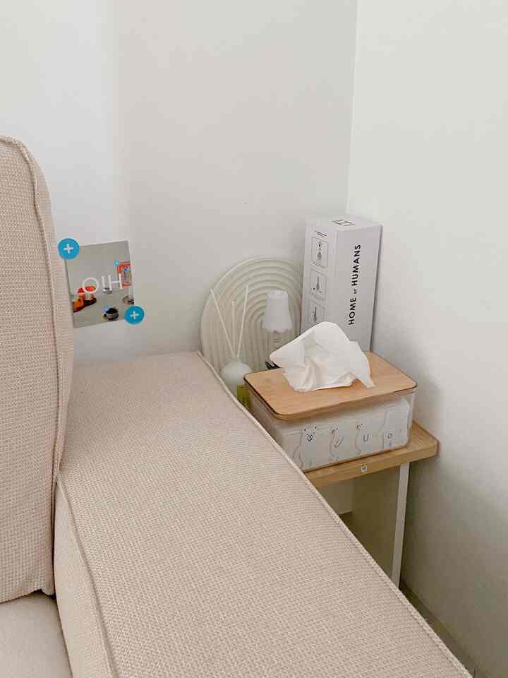 Bright white wall corner next to beige sofa with diffuser and tissue box, creating a natural style space