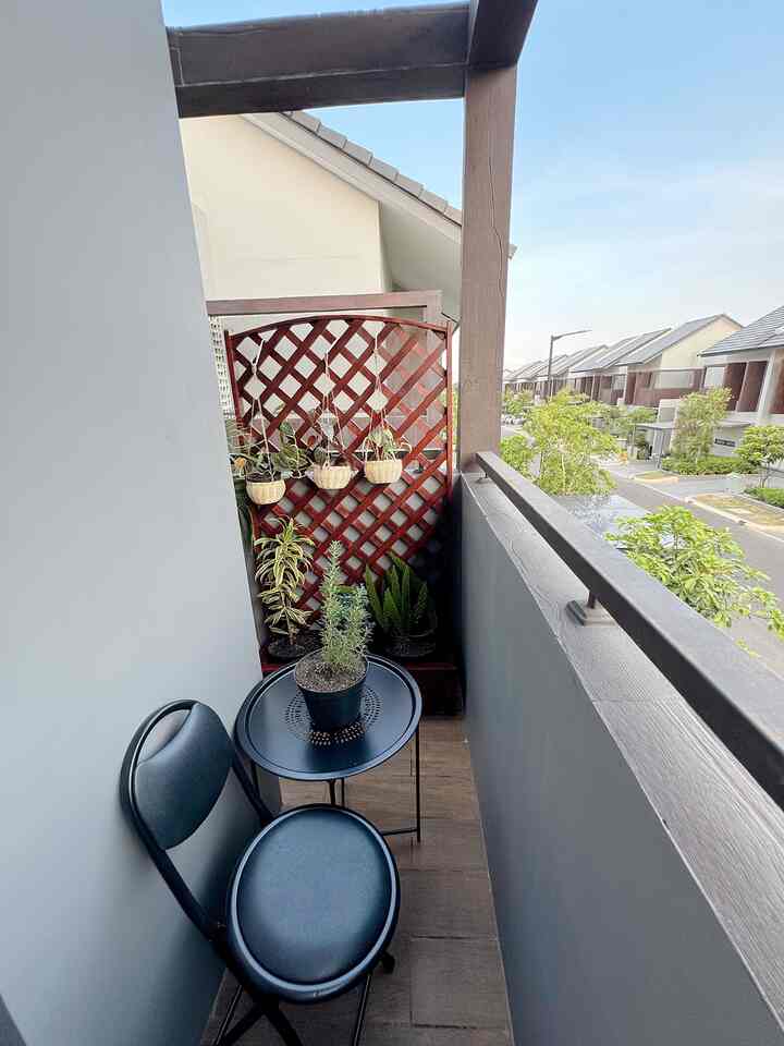 Natural tones and black minimalist small balcony featuring black folding chair and table with various plants creating cozy atmosphere