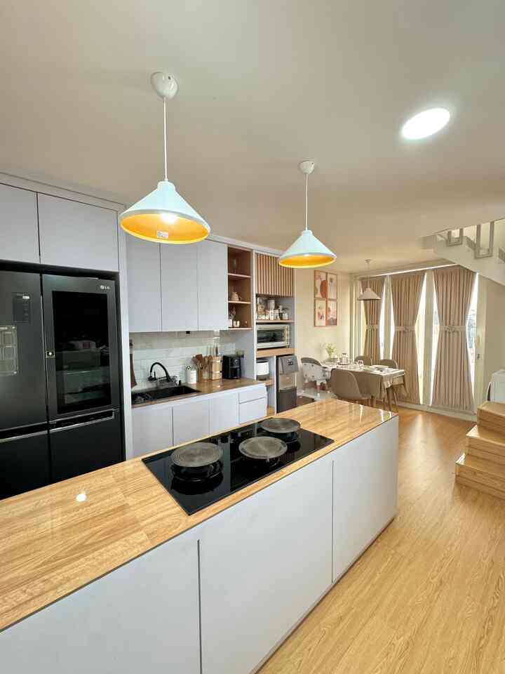 Bright white and wood-tone open space kitchen and dining room featuring a kitchen island and pendant lights with cozy warmth