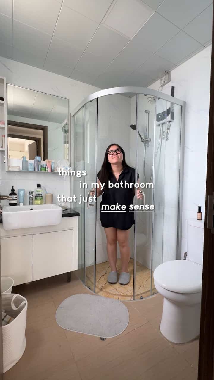 White and beige toned bathroom featuring a shower booth, wash basin, and bath mat with a clean and functional design