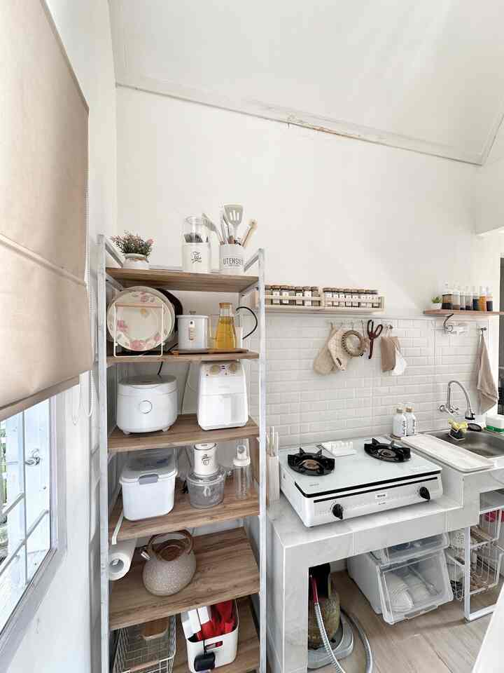 A clean kitchen space with white walls and tiles, and wood tone shelves organizing kitchen utensils