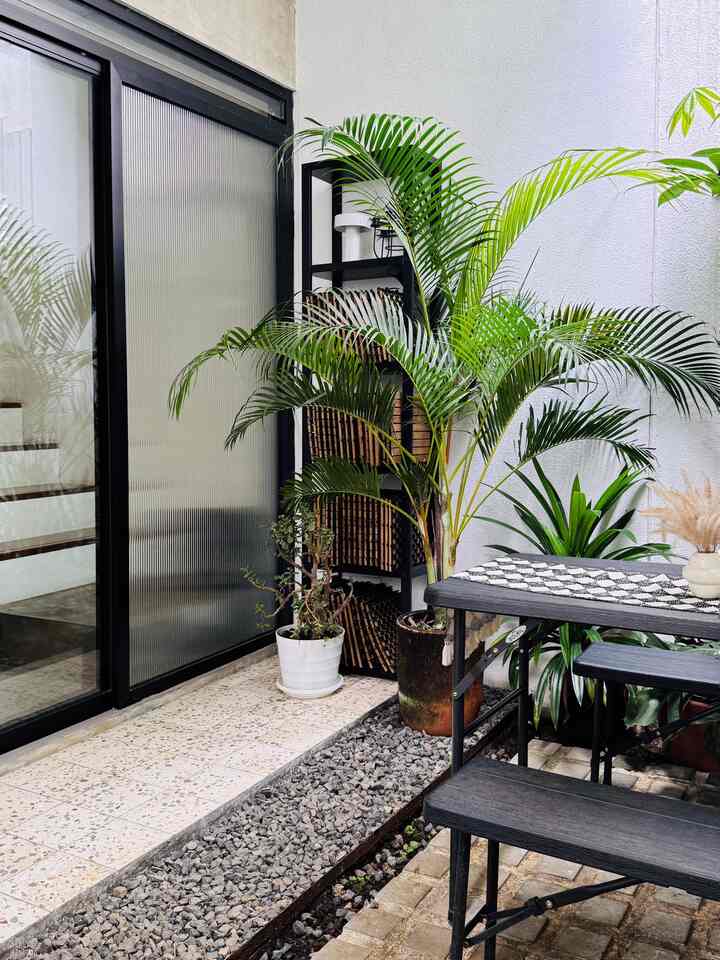 Modern and natural balcony space featuring black wood table and bench with various green plants