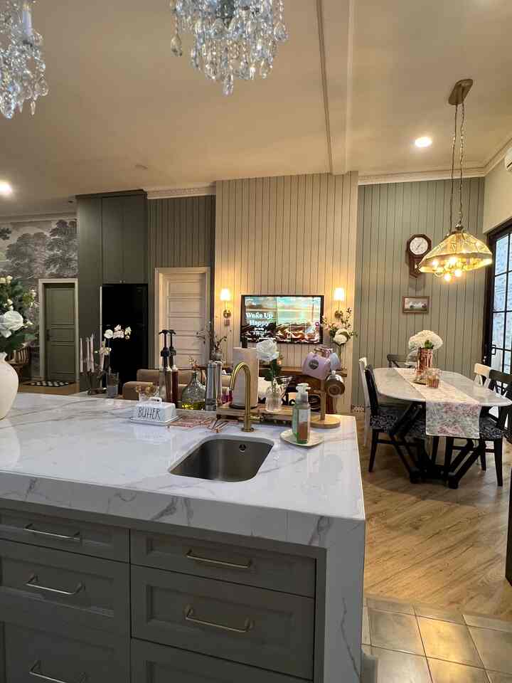 Wood tone dining room featuring a white marble kitchen island with gold faucet and a crystal chandelier, creating elegant atmosphere
