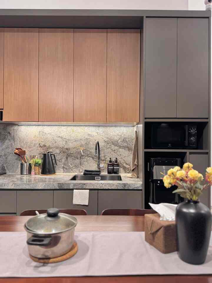 Modern kitchen with harmonious gray and wood tones, featuring a clean sink area and dining table in a cozy setting
