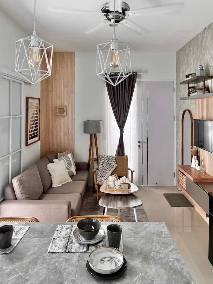 White and brown toned living and dining area featuring sectional sofa, pendant lights, and open modern minimalist design