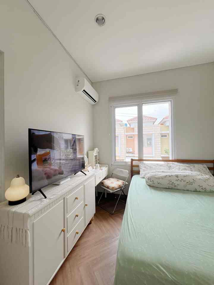 White and wood tone compact bedroom featuring multifunctional vanity by the window and a bed, showcasing minimal interior design