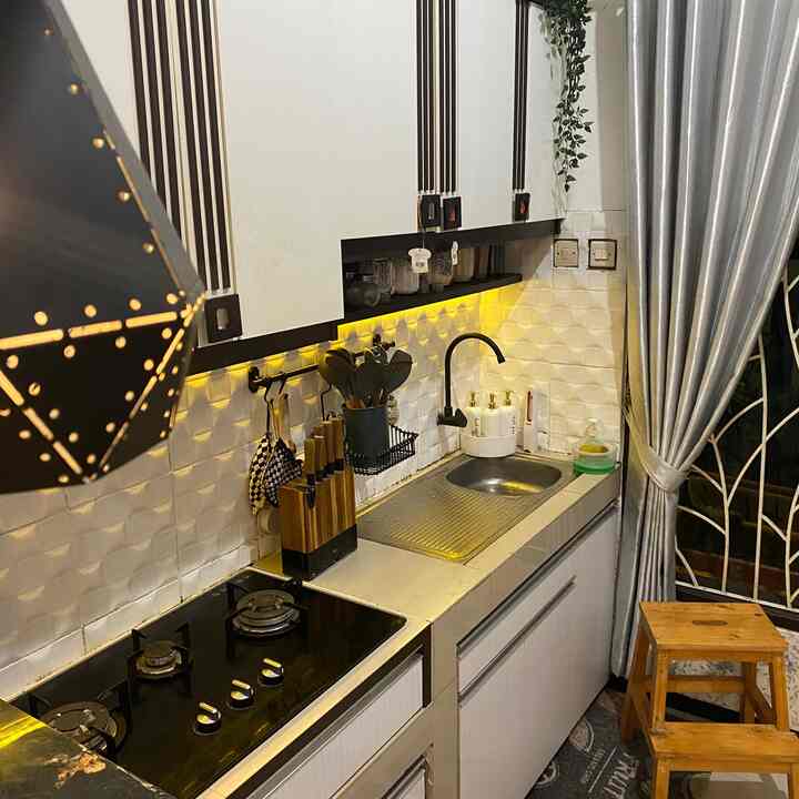 A modern kitchen space featuring white and wood tones, with a cleanly arranged sink and gas stove