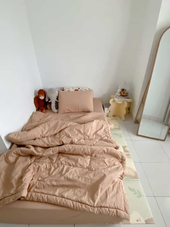 Beige bedding and baby playmat in a small bedroom with white walls and tiled floor, creating a cozy and clean space