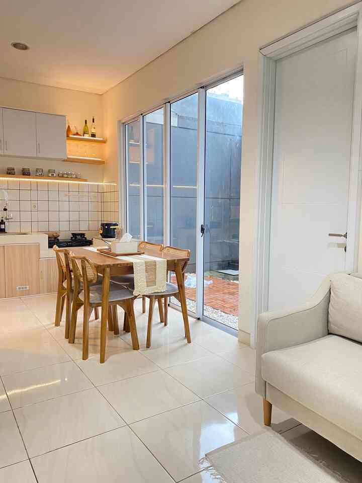 Bright beige and white toned dining room featuring natural wood dining table and chairs, white walls and cabinetry creating a cozy ambiance
