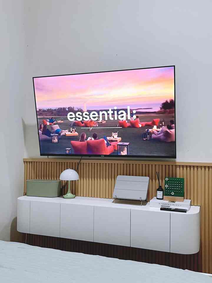 Minimal style bedroom featuring beige wood panel and white wall-mounted TV stand with clean layout