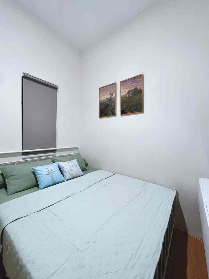 Compact bedroom with white walls and mint green bedding creating a simple, natural atmosphere