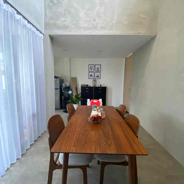 White walls and curtains, brown dining table and chairs in a dining room suited for a 4-person household