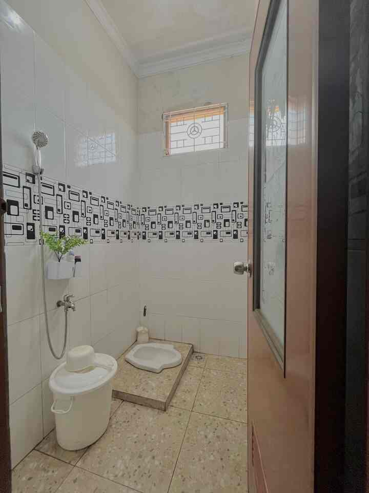 Compact white bathroom with black tile pattern accents, featuring minimal essential bathroom accessories for a clean and functional space