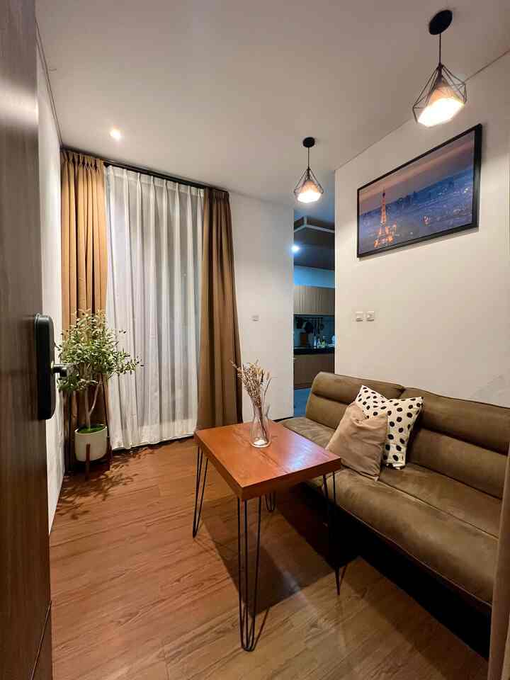 Warm brown and wood tone compact living room featuring a 2-seater sofa bed, wooden coffee table, pendant lights, and a decorative plant creating a cozy atmosphere