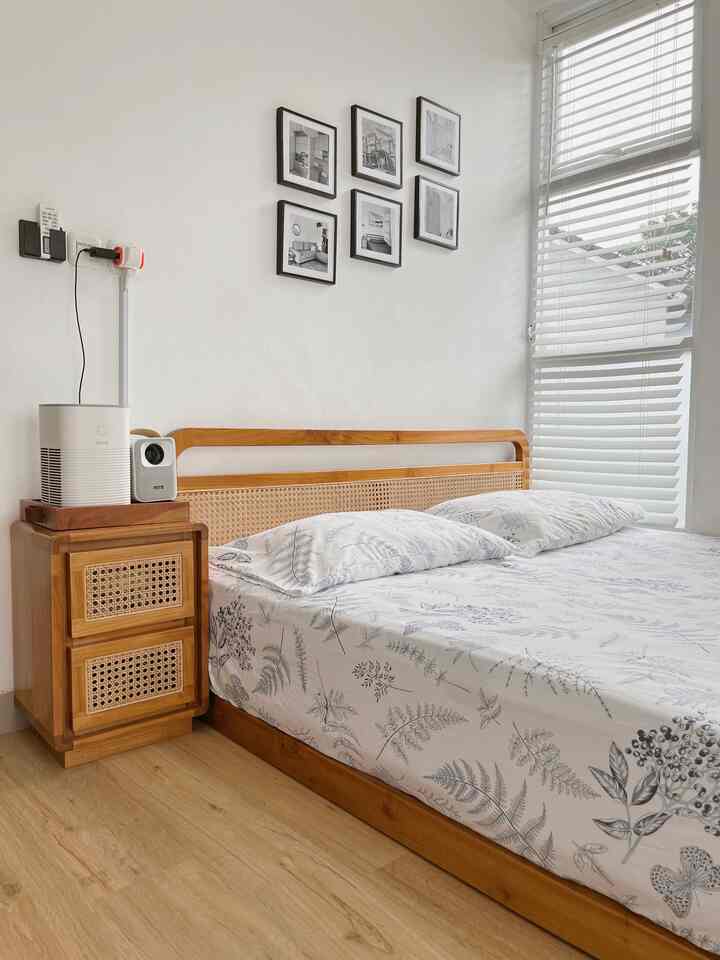 Natural wood tones and white colors in a minimal modern bedroom featuring a bed, nightstand, and Roman blinds by the window creating a cozy atmosphere